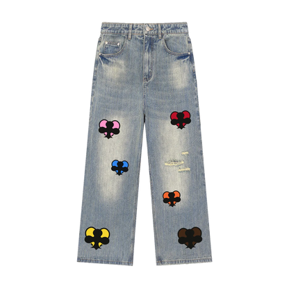 Light blue denim jeans with distressed rips and colorful embroidered patch designs featuring black spades with pink, red, blue, orange, yellow, and dark brown details, shown flat on a white background.